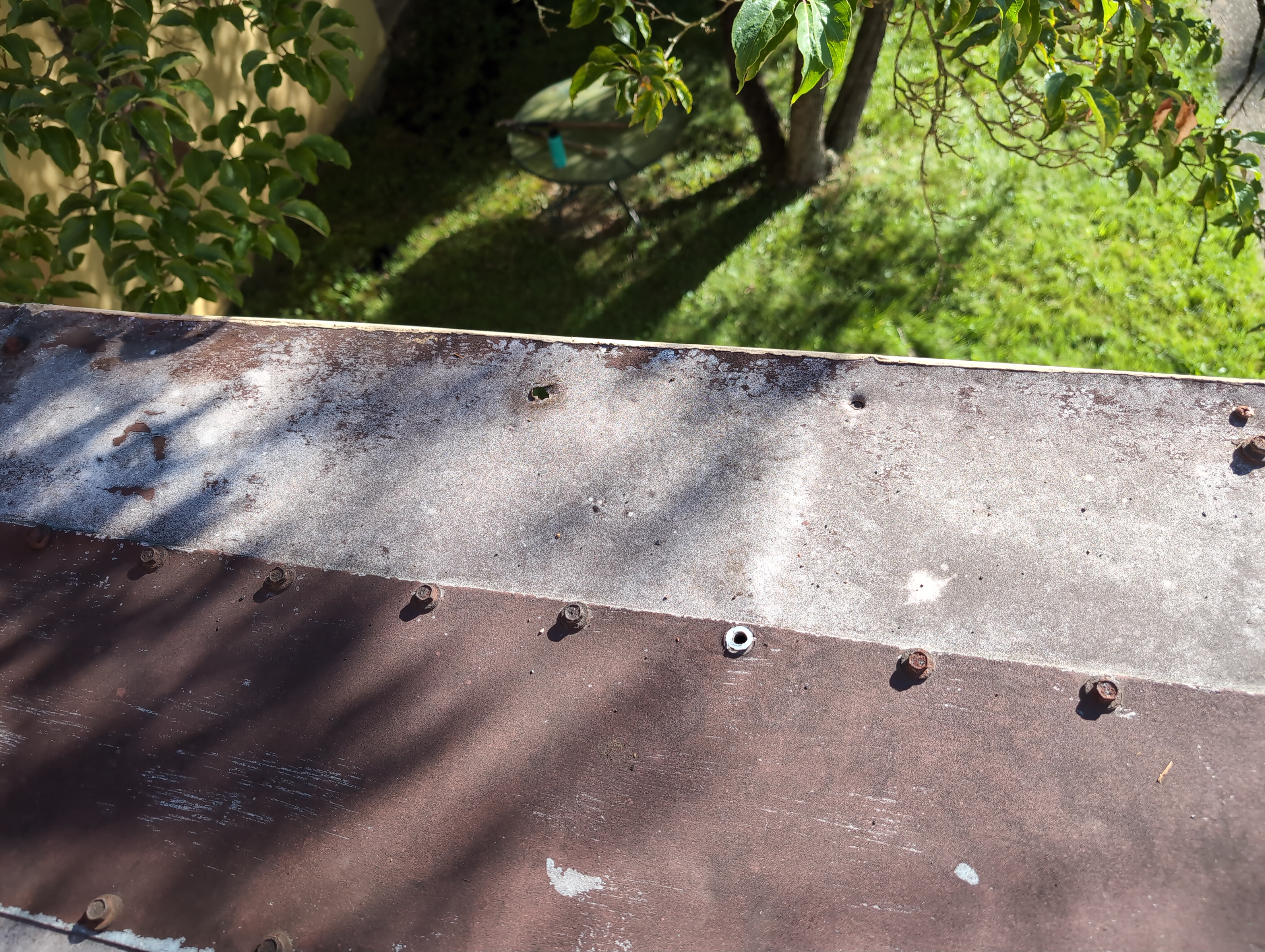 A deeper section of top of wall covered in metal, in multiple panels. Three holes exist where there clearly should be bolts.